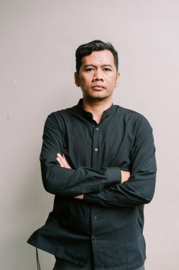 Kollarını kavuşturup kameraya bakan kendinden emin, olgun bir adam. Siyah gömlekli başarılı iş adamının stüdyo fotoğrafı..