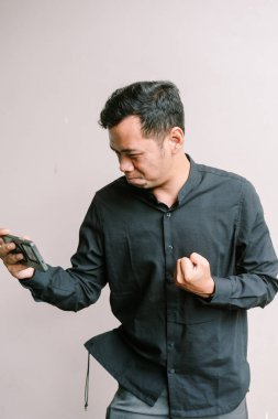 Hevesli bir adam akıllı telefonuyla oyun oynarken heyecanlanıyor. Yüzünde neşeli bir ifade vardı..