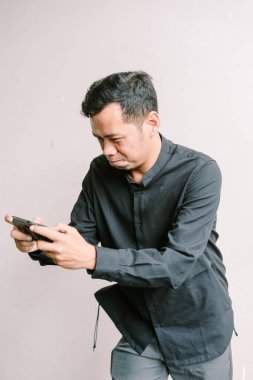 Ciddi bir adam kapalı alanda akıllı telefonuyla oyun oynarken konsantre oluyor.