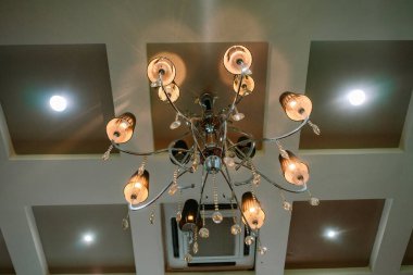 Tavandan sarkan süslü bir avize iç mekâna biraz zarafet katıyor. Dekoratif süsleme ve aydınlatma armatürleri.