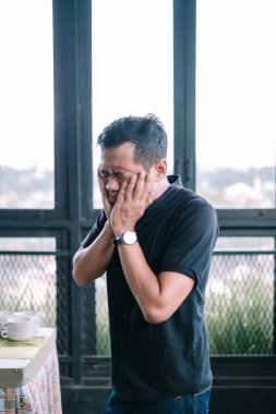 Endişeli adam elleriyle yüzünü kapatıyor. Stres ve duygusal çöküntünün portresi. Endişe ve üzüntü iletiliyor..