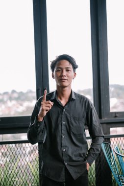 Sıradan giyinmiş genç Asyalı adam, şehir geçmişine işaret ediyor. Tavsiye veya ilham için kavram