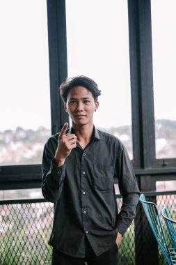 Olumlu ifadeli genç adam yukarı doğru işaret ediyor. Şehir ortamında yeni bir fikir, konsept, öneri