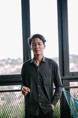 Siyah gömlekli düşünceli genç adam büyük bir pencereden dışarı bakıyor. Kapalı bir portre, rahat bir tarz ve rahat bir ifade.