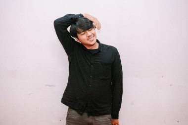 Genç bir adam yüzünü buruşturarak rahatsız edici ya da gergin bir şekilde boynunu uzatır. Basit bir arkaplanda izole edilmiş.