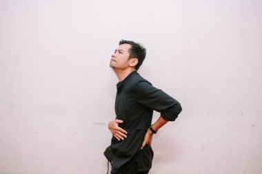 Mide ağrısı çeken bir adam. Kendini iyi hissetmiyor ve acılı bölgesine baskı yapıyor. Asyalı erkek karın rahatsızlığı yaşıyor