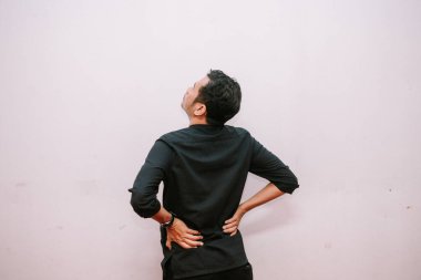 Sırtı ağrıyan üzgün bir adam yukarı bakarken sırtına dokunuyor. Sağlık sorunları için kavram