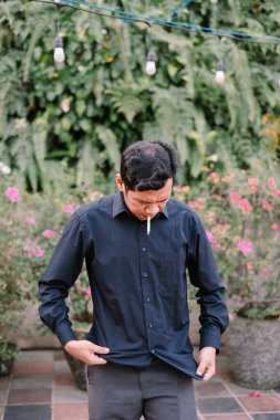 Adam bahçe ortamında düşünceli bir şekilde sigara içiyor. Yakın çekim görünümü.