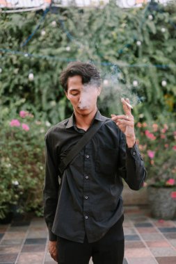 Düşünceli bir adam güzel bir bahçenin ortasında sigara içmekten zevk alır. Sahne, rahatlama ve iç gözlem anlarını anımsatıyor..