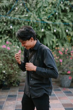 Mutlu genç adam dışarıda eğleniyor. Mutluluk ve tasasız enerjiyle dolu yeşil bir arka planda gülümsüyor..