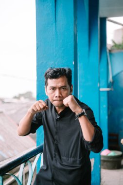 Kararlı Asyalı genç bir adam. Nefsi müdafaa için hazır. Kentsel arkaplan ve odaklanmış ifade.