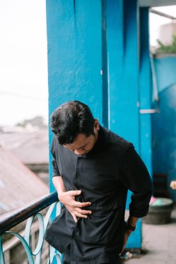 Karnını tutan endişeli bir adam, rahatsızlık ve acı çekiyor, sağlık problemi kavramı. Üzgün erkek karın spazmı belirtileri gösteriyor.