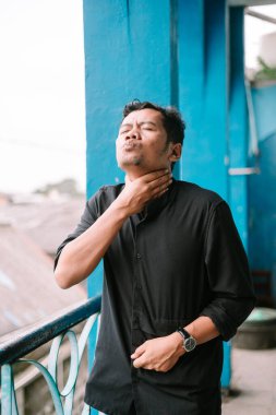 Boğazı ağrıyan Asyalı bir adam kendini rahatsız hissediyor. Sağlık, hastalık ve tıbbi konsept.