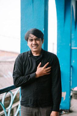 Göğsünü acı içinde tutan endişeli bir adam. Kalp rahatsızlığı hakkında endişeli görünüyor..