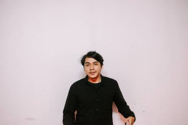 Rahatlamış genç bir adamın gizli bir fotoğrafı. Arkaplanı düz siyah bir gömlek giyiyor..