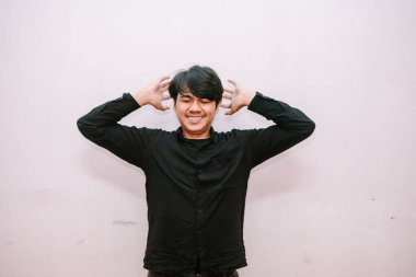 Basit bir stüdyo ortamında elleri başının üstünde hayal kırıklığını ifade eden genç bir adam.