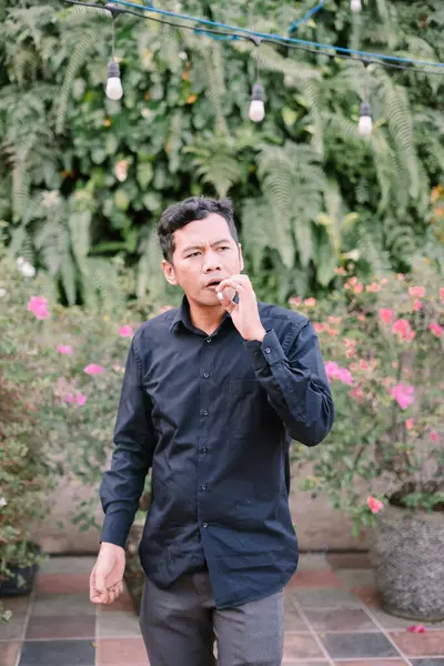 Açık havada sigara içen bir adam yemyeşil arka planda..