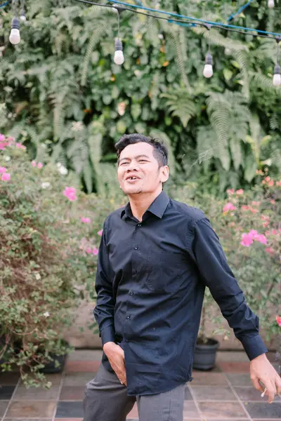 Sıradan bir adam, yeşil bir bahçenin ortasında rahat ve hoşnut bir atmosfer yayarak sigara içmekten zevk alır..