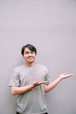 Gülümseyen Asyalı adam gri desenli arka plana karşı boş bir alan sunuyor. Metin veya grafikleriniz için yer.