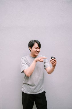 Hevesli genç adam telefonunu işaret ediyor. Yeni cep telefonu uygulamasını gösteriyor..