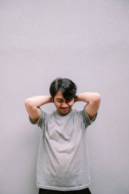 Sıradan giyinmiş Asyalı bir adam elleri başının arkasında gri bir arka plana doğru gülümsüyor. Sakin ve huzurlu bir an..