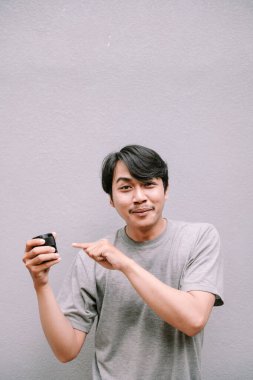 Çekici Asyalı adam elindeki küçük siyah kavanozu göstererek bir ürünü tanıtıyor..