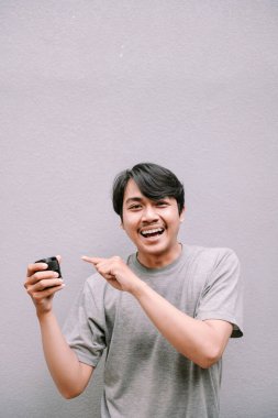 Neşeli adam küçük siyah bir kavanozu işaret ediyor. El hareketleriyle izole edilmiş, ışık desenli duvarda fotokopi alanı olan.