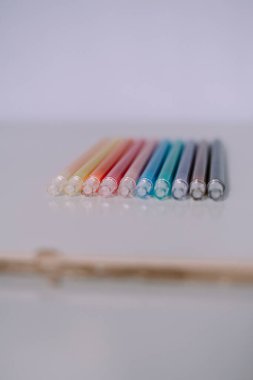 Pastel renkli fırça kalemlerinin olduğu bir sıra yakın plan. Arkaplan, grafik projeleri veya yaratıcılığı temsil etmek için ideal.