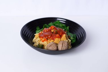 Mie Ayam, Endonezya 'nın popüler yemeği, tavuk, köfte ve yeşil sebzelerle servis ediliyor. Beyaz yüzeyde yakın plan.