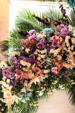 İçinde güller, orkideler ve palmiye yaprakları olan güzel bir çiçek aranjmanı. Düğünler, etkinlikler ya da dekoratif amaçlar için mükemmel.