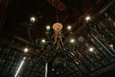 İçerideki ahşap tavandan sarkan ışıklarla süslü bir avizenin düşük açılı görüntüsü sıcak ve davetkar bir ortam yaratıyor..