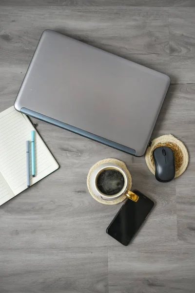 Kahve fincanı, dizüstü bilgisayar ve defter ofiste.