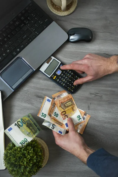 Ofiste bilgisayar kullanan, çalışan ve para sayan biri.