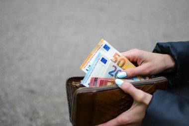 Kadın çantadan para alıyor.