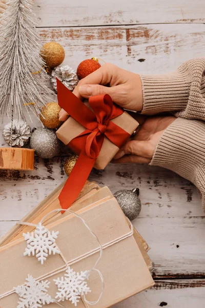 Küçük Noel hediyelerini paketleyen kadın elleri, masanın üzerindeki süslemeler.