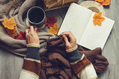 Woman hands knitting woolen sweater, working space indoors, coffee and vintage stuff around clipart