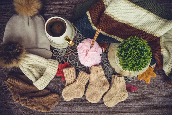 Sonbahar yapraklı bir fincan kahve ve ahşap arka planda örülmüş eşarp.
