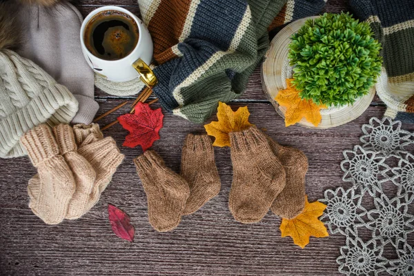Sonbahar yapraklı bir fincan kahve ve ahşap arka planda örülmüş eşarp.