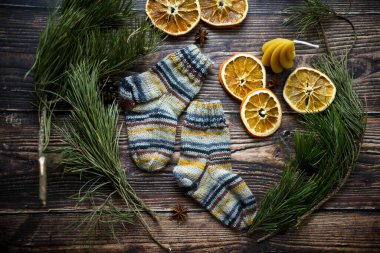 Renkli el örgüsü çocuklara çorap ve koyu ahşap arka planda kurutulmuş portakal dilimleri.