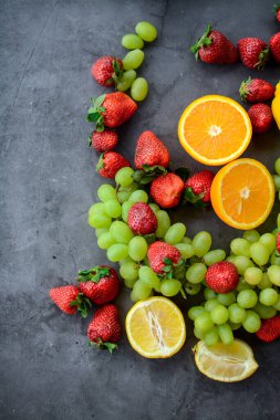 Mutfakta koyu gri arka planda çeşitli meyve ve meyveler var.