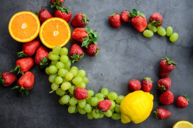 Mutfakta koyu gri arka planda çeşitli meyve ve meyveler var.