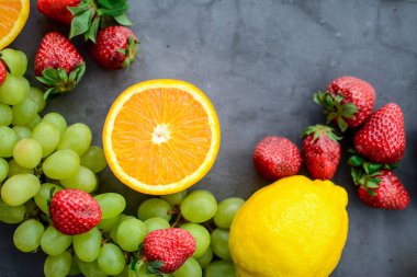 Mutfakta koyu gri arka planda çeşitli meyve ve meyveler var.