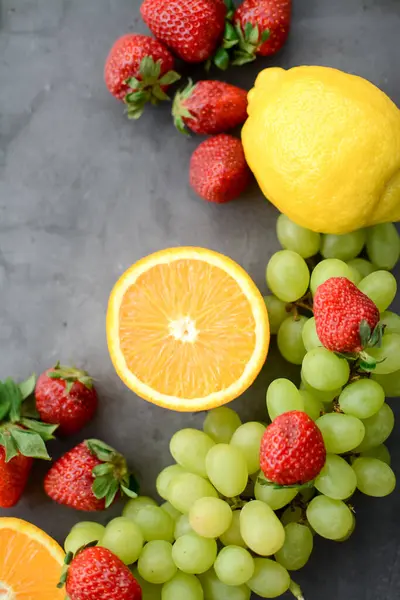 Mutfakta koyu gri arka planda çeşitli meyve ve meyveler var.