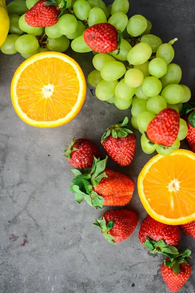 Mutfakta koyu gri arka planda çeşitli meyve ve meyveler var.