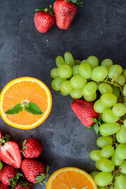 Koyu arkaplanda çeşitli meyve ve meyveler var.