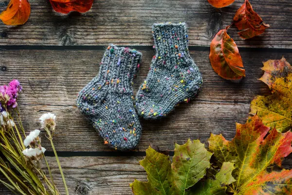 Renkli el örgüsü çocuklara çorap ve koyu ahşap arka planda kurutulmuş portakal dilimleri.