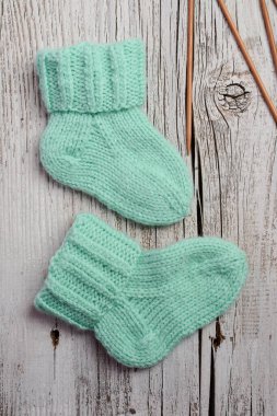 Yumuşak pamuktan yapılmış nane yeşili bebek çorapları, ahşap masadaki yeni doğan için mükemmel bir hediye.