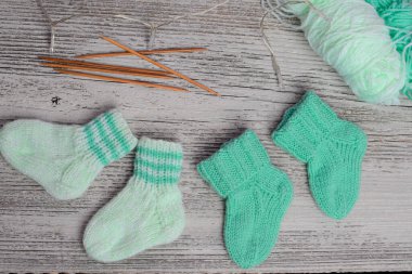 Yumuşak pamuktan yapılmış nane yeşili bebek çorapları, ahşap masadaki yeni doğan için mükemmel bir hediye.