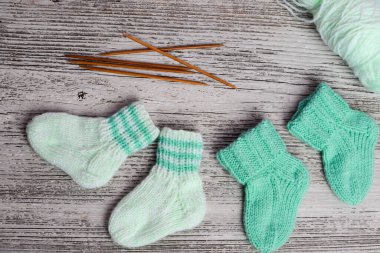 Yumuşak pamuktan yapılmış nane yeşili bebek çorapları, ahşap masadaki yeni doğan için mükemmel bir hediye.