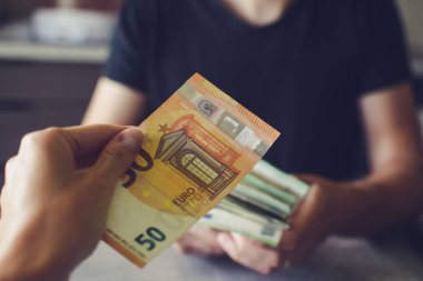 Avro banknotları adamın elinde, karanlık odada para sayıyor.